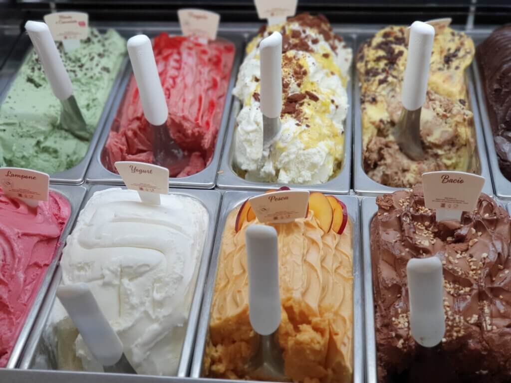 Two rows of various ice cream flavors in tubs, each with its own spoon