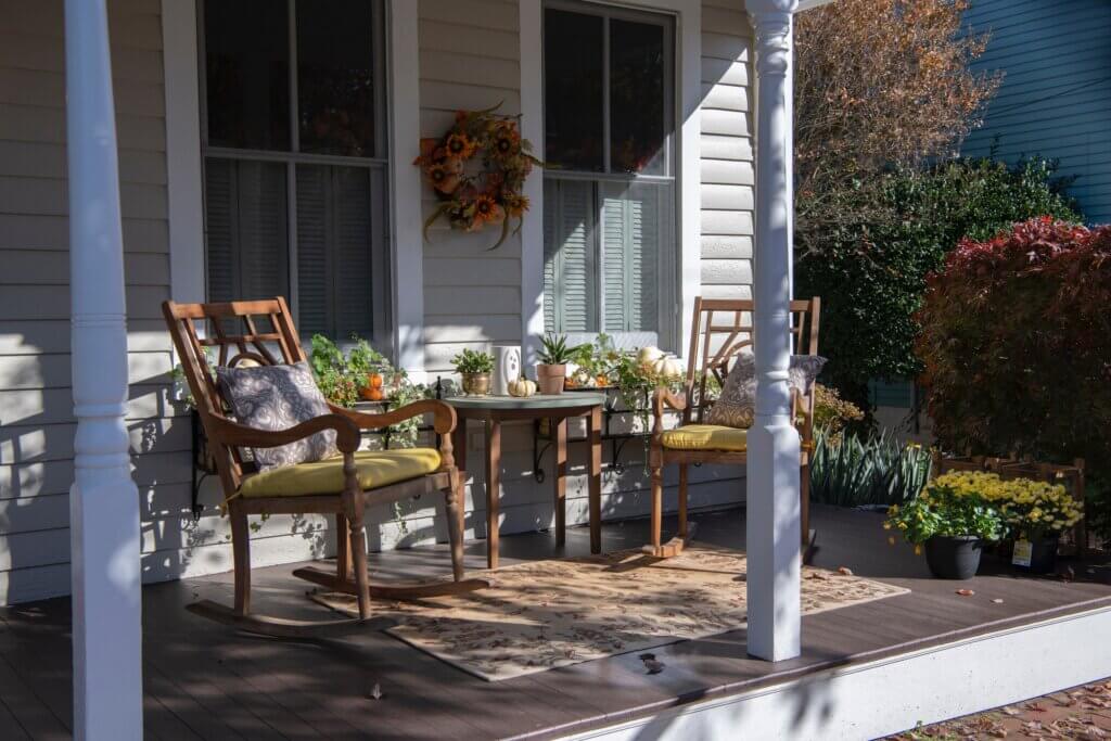 A front porch with two rocking chairs, a small table, and a fall wreath