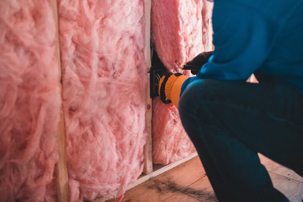 person inserting insulation into a wall