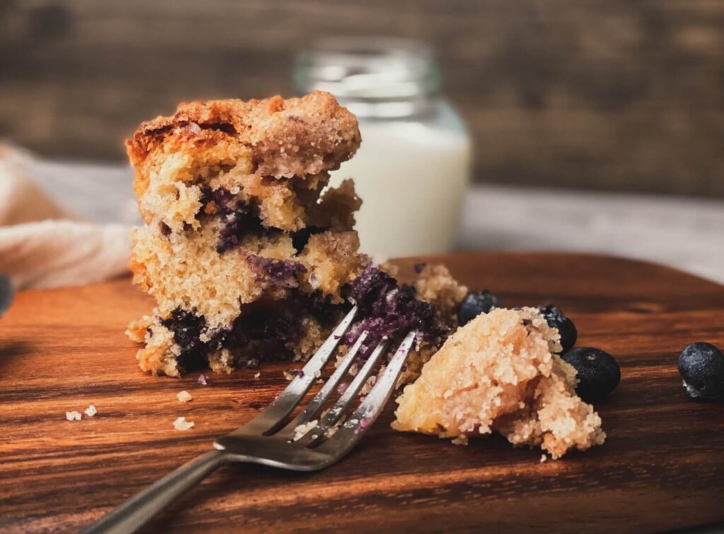 Blueberry buckle, with a fork, on a wooden cutting board