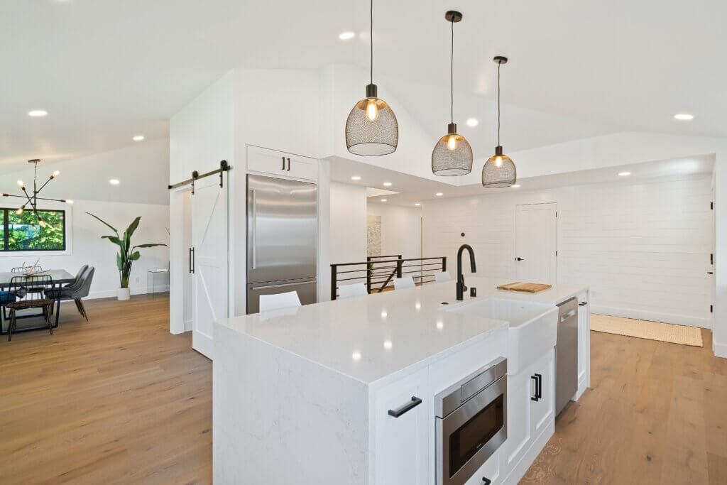 white kitchen island with three black wire pendant lights above it