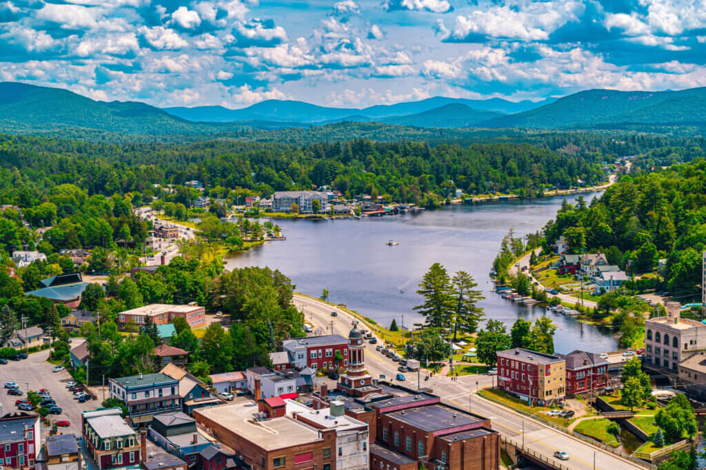 View of the town of Saranac Lake in the foreground, with the lake and mountains in the background