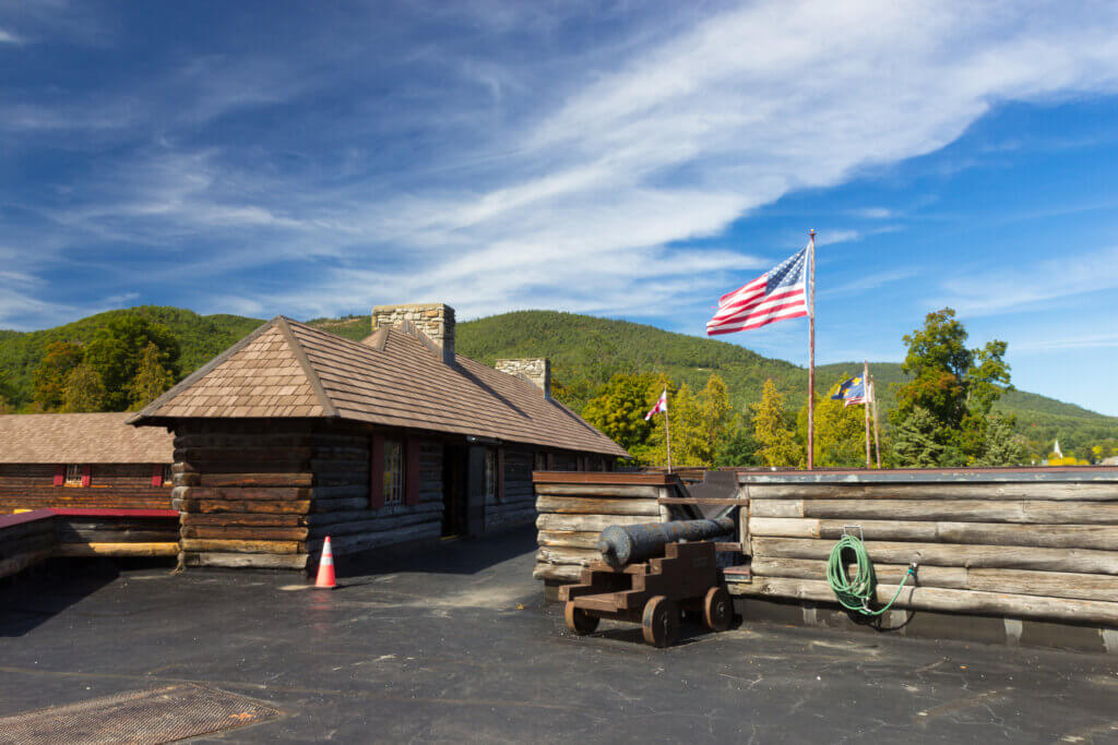 Wood fort with canon and American flag in the foreground, view of mountains in the background