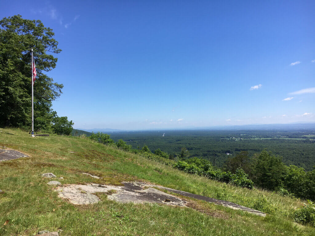 Grassy hill with American flag overlooking the green valley below